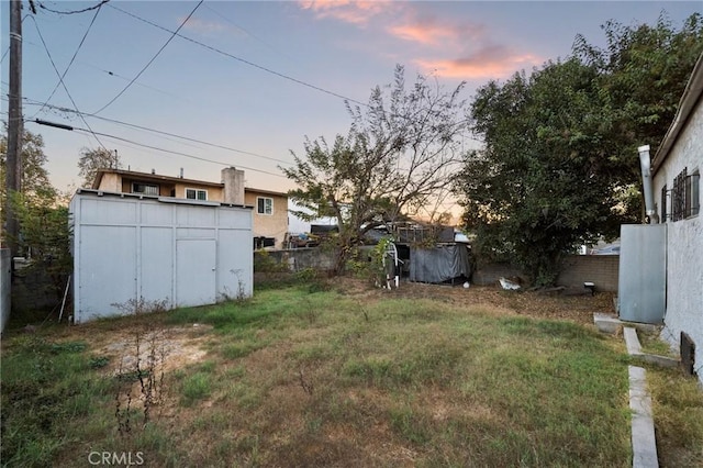 yard at dusk featuring a storage unit