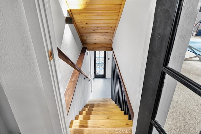 staircase featuring wood-type flooring and wooden ceiling