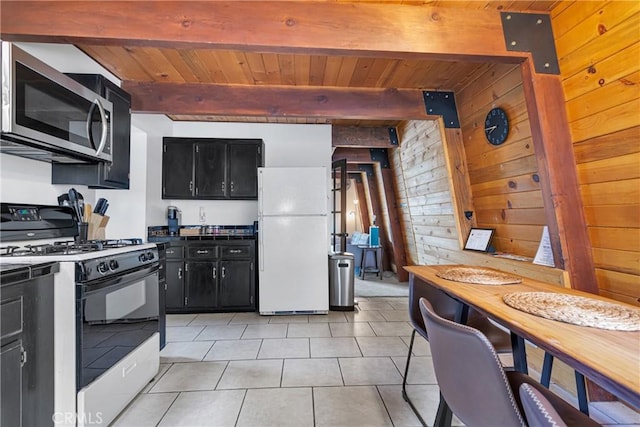 kitchen with wood walls, beamed ceiling, light tile patterned flooring, and white appliances