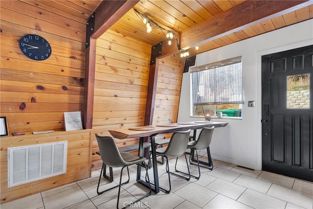 dining area featuring light tile patterned flooring, wood walls, beamed ceiling, and wood ceiling