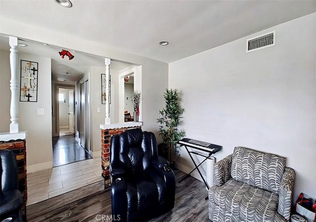 living area with dark wood-type flooring and decorative columns