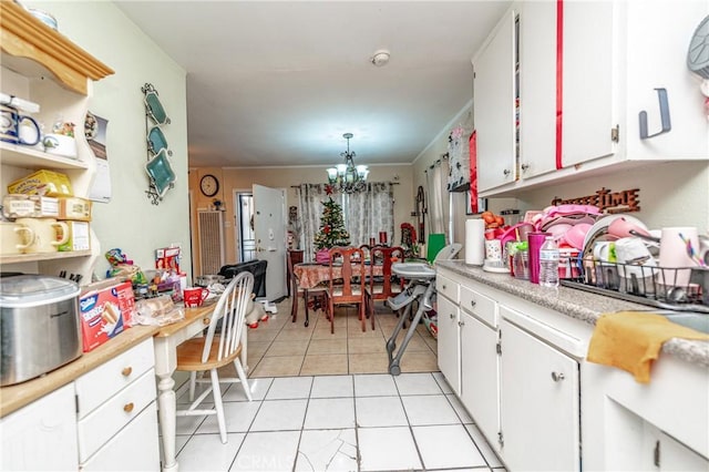 kitchen with a notable chandelier, white cabinets, ornamental molding, decorative light fixtures, and light tile patterned flooring