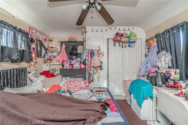 interior space with ceiling fan, dark carpet, a textured ceiling, and a closet