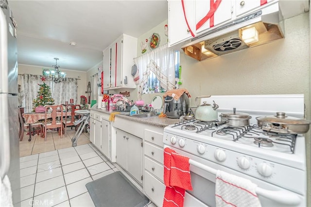 kitchen with white cabinets, white gas range oven, hanging light fixtures, stainless steel fridge, and a chandelier