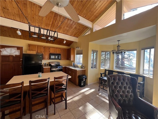 kitchen featuring pendant lighting, black appliances, ceiling fan with notable chandelier, sink, and beamed ceiling