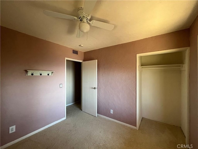 unfurnished bedroom featuring ceiling fan, a closet, and light colored carpet