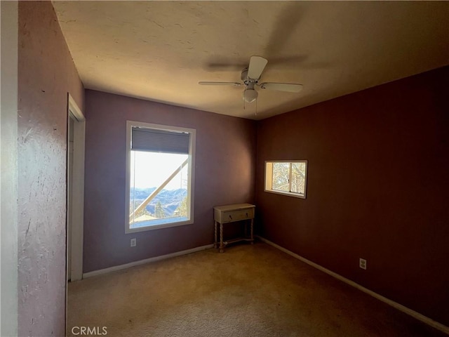 carpeted spare room featuring a wealth of natural light and ceiling fan