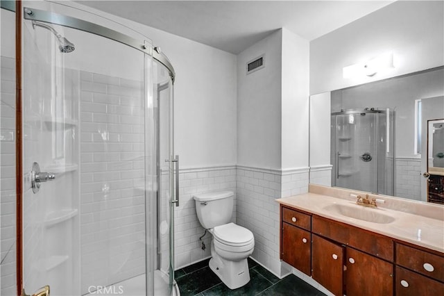 bathroom featuring tile patterned flooring, vanity, a shower with shower door, and tile walls