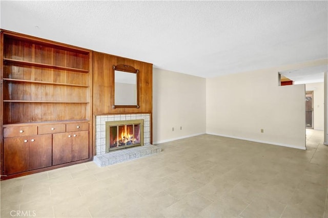 unfurnished living room with a tiled fireplace and a textured ceiling