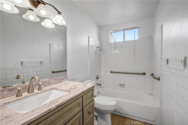 full bathroom with tiled shower / bath, hardwood / wood-style floors, vanity, and toilet