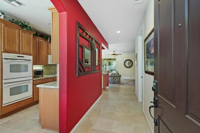 kitchen featuring ceiling fan, white double oven, light stone countertops, tasteful backsplash, and light tile patterned floors