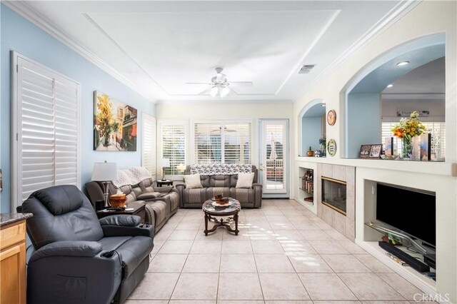 2028 Melbourne Cir, Banning, CA 92220 - living area featuring a ceiling fan, light tile patterned floors, crown molding, a tray ceiling, and a tile fireplace