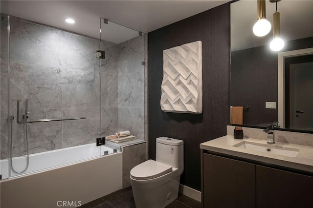 full bathroom with combined bath / shower with glass door, vanity, tile walls, tile patterned flooring, and toilet