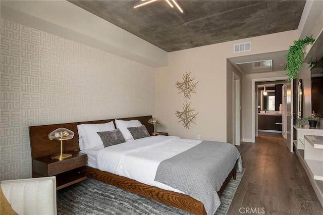 bedroom with dark hardwood / wood-style flooring and connected bathroom