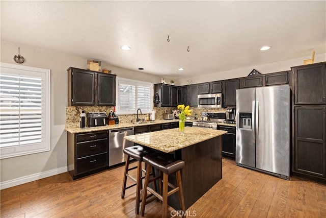 kitchen featuring a kitchen breakfast bar, sink, appliances with stainless steel finishes, and light hardwood / wood-style flooring