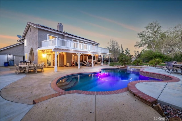 pool at dusk with an in ground hot tub and a patio