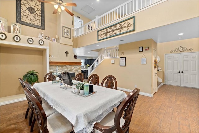 dining space featuring ceiling fan, a high ceiling, and light hardwood / wood-style flooring