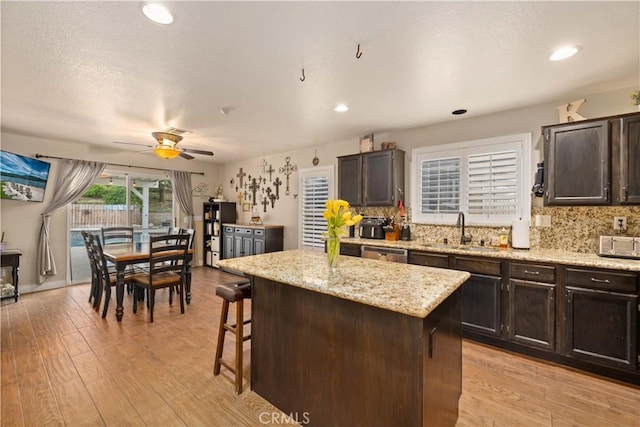 kitchen featuring light wood-type flooring, a center island, dark brown cabinetry, and sink