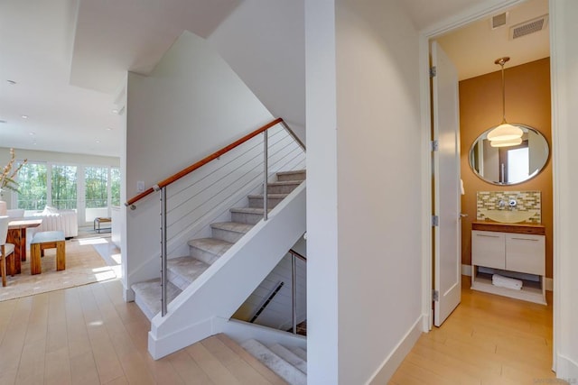 stairs featuring wood-type flooring and sink