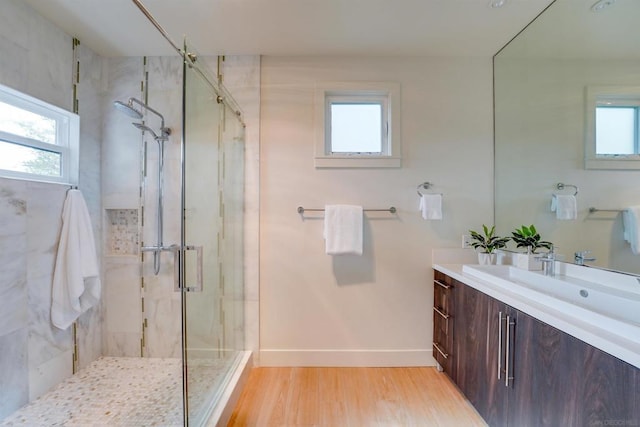 bathroom featuring hardwood / wood-style floors, vanity, a shower with shower door, and a healthy amount of sunlight