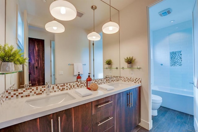 full bathroom with vanity, tiled shower / bath, hardwood / wood-style flooring, toilet, and tasteful backsplash