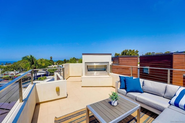 view of patio with an outdoor living space with a fireplace and a balcony