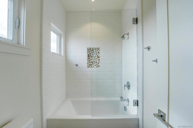 bathroom featuring a wealth of natural light, tiled shower / bath combo, and toilet