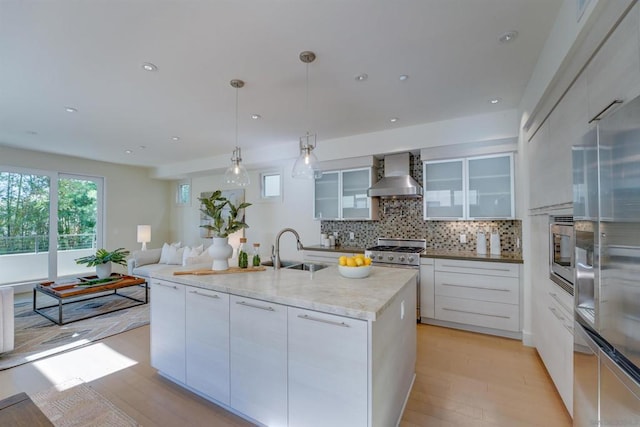 kitchen featuring pendant lighting, white cabinetry, wall chimney exhaust hood, and sink