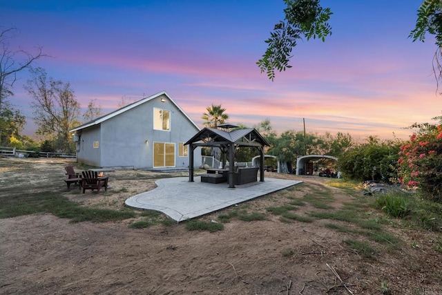 back house at dusk featuring a gazebo, a patio area, and an outdoor hangout area