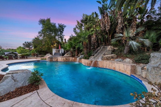 pool at dusk featuring pool water feature