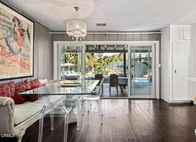 unfurnished dining area with crown molding, breakfast area, hardwood / wood-style floors, a chandelier, and wooden walls