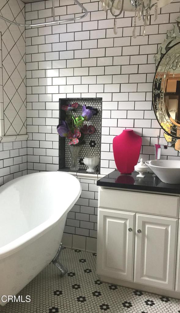 bathroom featuring a bath, vanity, tile patterned floors, and tile walls