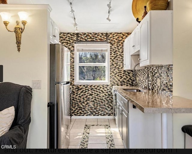 kitchen with stainless steel fridge, track lighting, sink, light tile patterned floors, and white cabinets