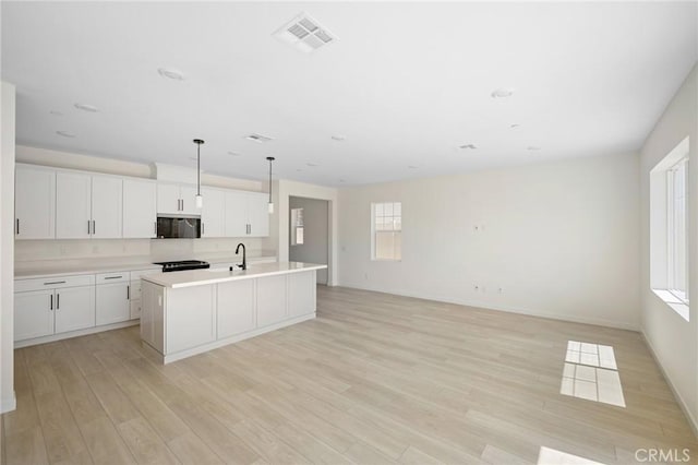 kitchen with light wood-type flooring, a center island with sink, white cabinets, black range with electric stovetop, and hanging light fixtures