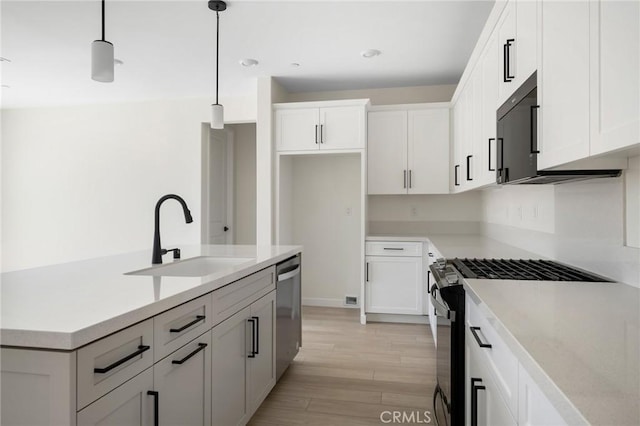 23724 Wilcox Dr, Newhall, CA 91321 - kitchen with stainless steel appliances, light wood-style flooring, white cabinets, and decorative light fixtures