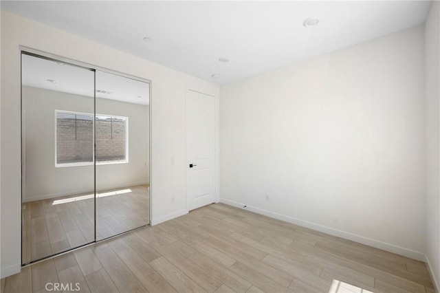 unfurnished bedroom with a closet and light hardwood / wood-style floors