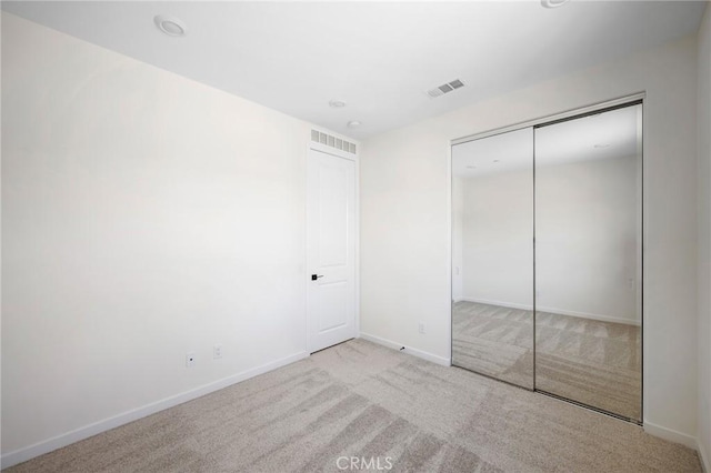 unfurnished bedroom with light carpet and a closet