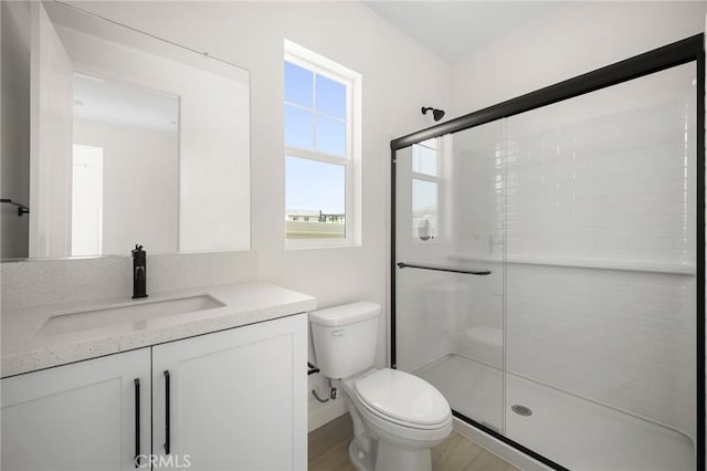 bathroom with a shower with door, vanity, and toilet