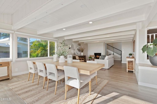 dining room with light wood-style floors, beamed ceiling, stairway, and baseboards