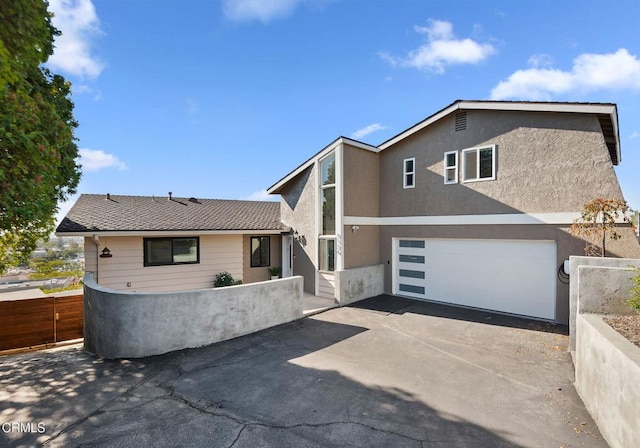 view of front of home featuring an attached garage, fence, concrete driveway, stucco siding, and a patio area