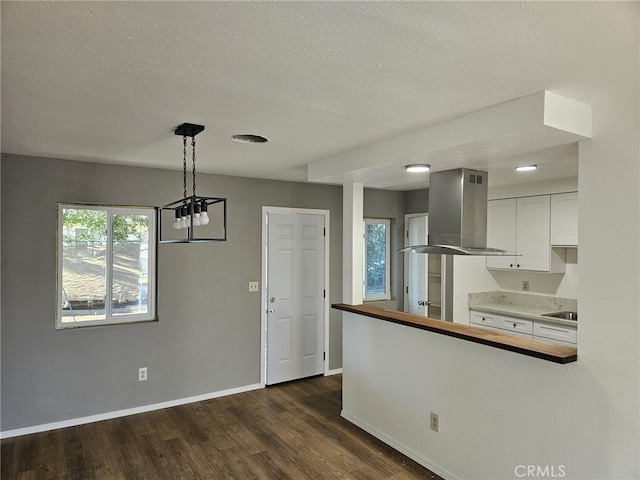 kitchen featuring dark hardwood / wood-style flooring, a textured ceiling, decorative light fixtures, white cabinets, and exhaust hood