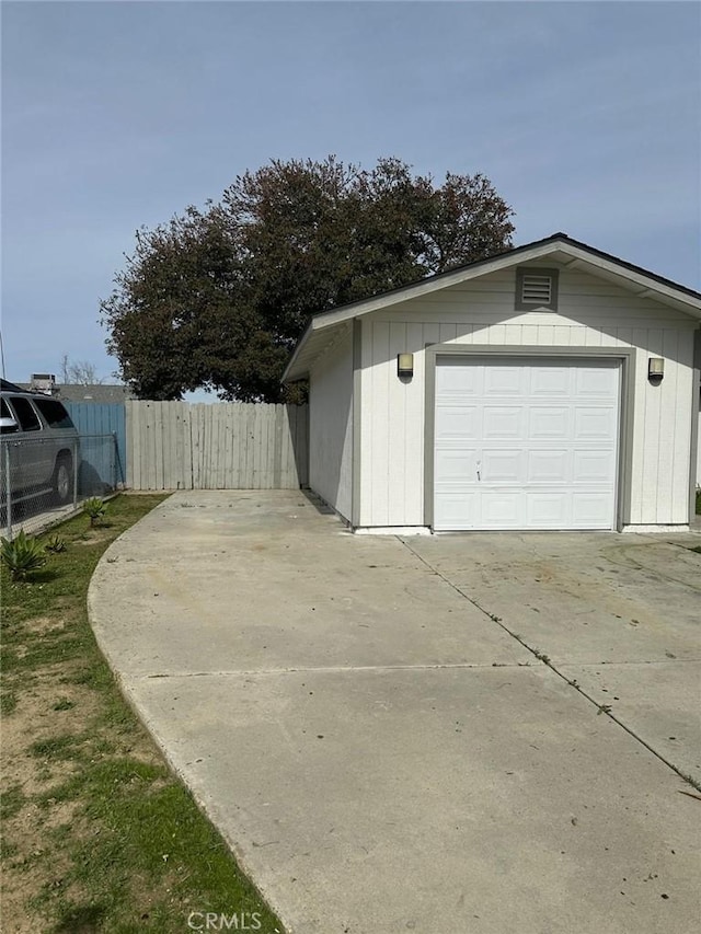 garage featuring driveway and fence