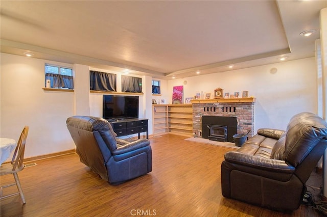 living room with hardwood / wood-style floors, a wood stove, and a raised ceiling