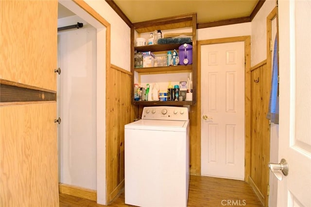 clothes washing area with wood walls, wood-type flooring, and washer / dryer