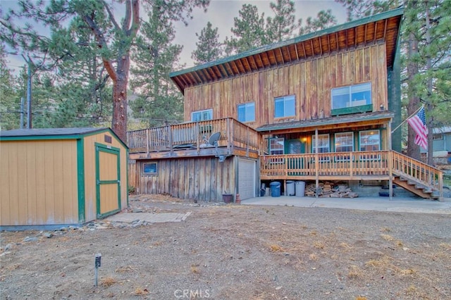 rear view of house with a wooden deck and a storage shed