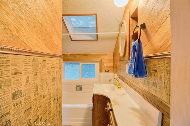 bathroom featuring vanity, a washtub, and a skylight