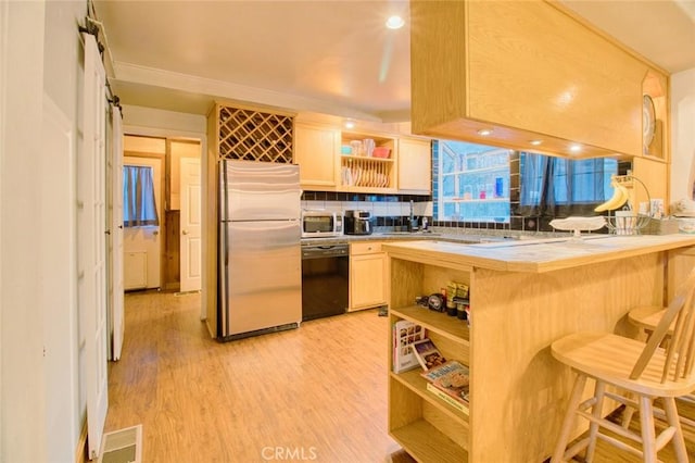 kitchen with tile countertops, light hardwood / wood-style flooring, appliances with stainless steel finishes, a kitchen bar, and kitchen peninsula