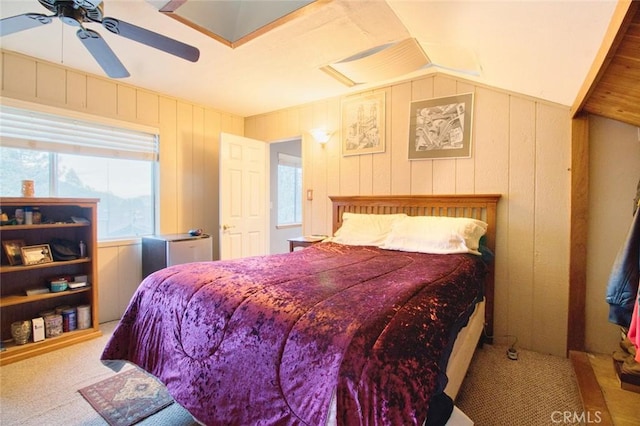 carpeted bedroom featuring vaulted ceiling, ceiling fan, and wood walls