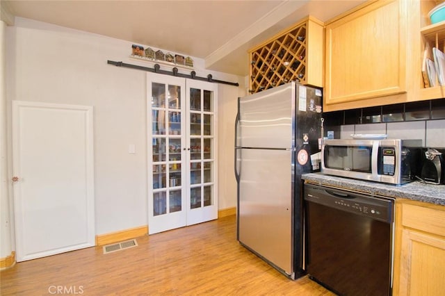 kitchen with appliances with stainless steel finishes, a barn door, light hardwood / wood-style floors, and light brown cabinets