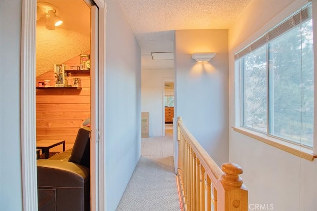 corridor featuring light carpet, a textured ceiling, and wood walls